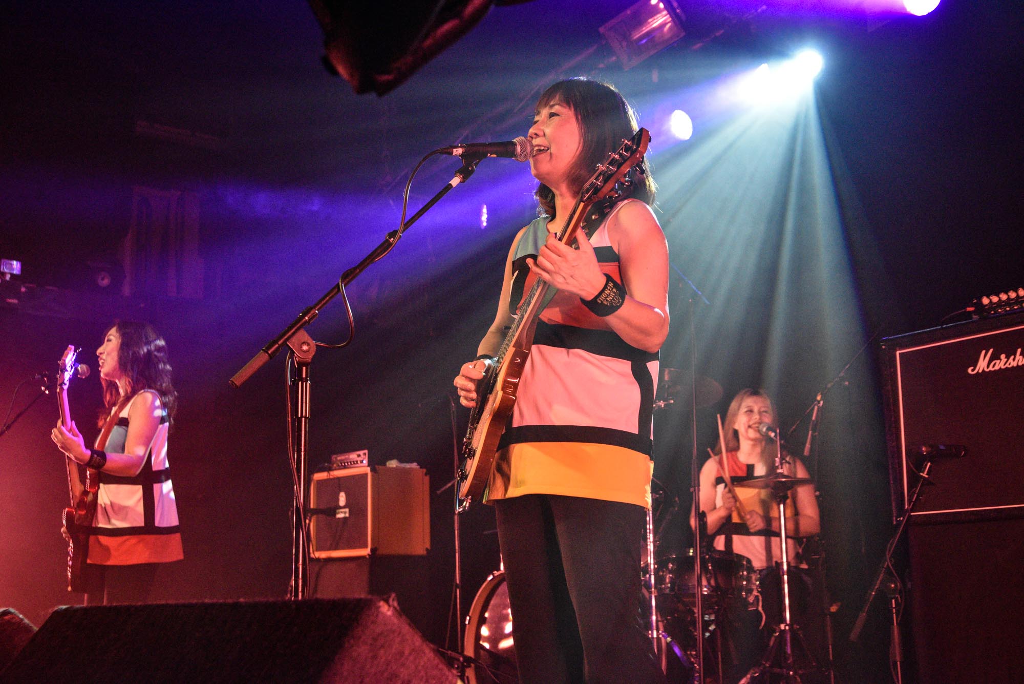 Three band members in matching outfits on stage