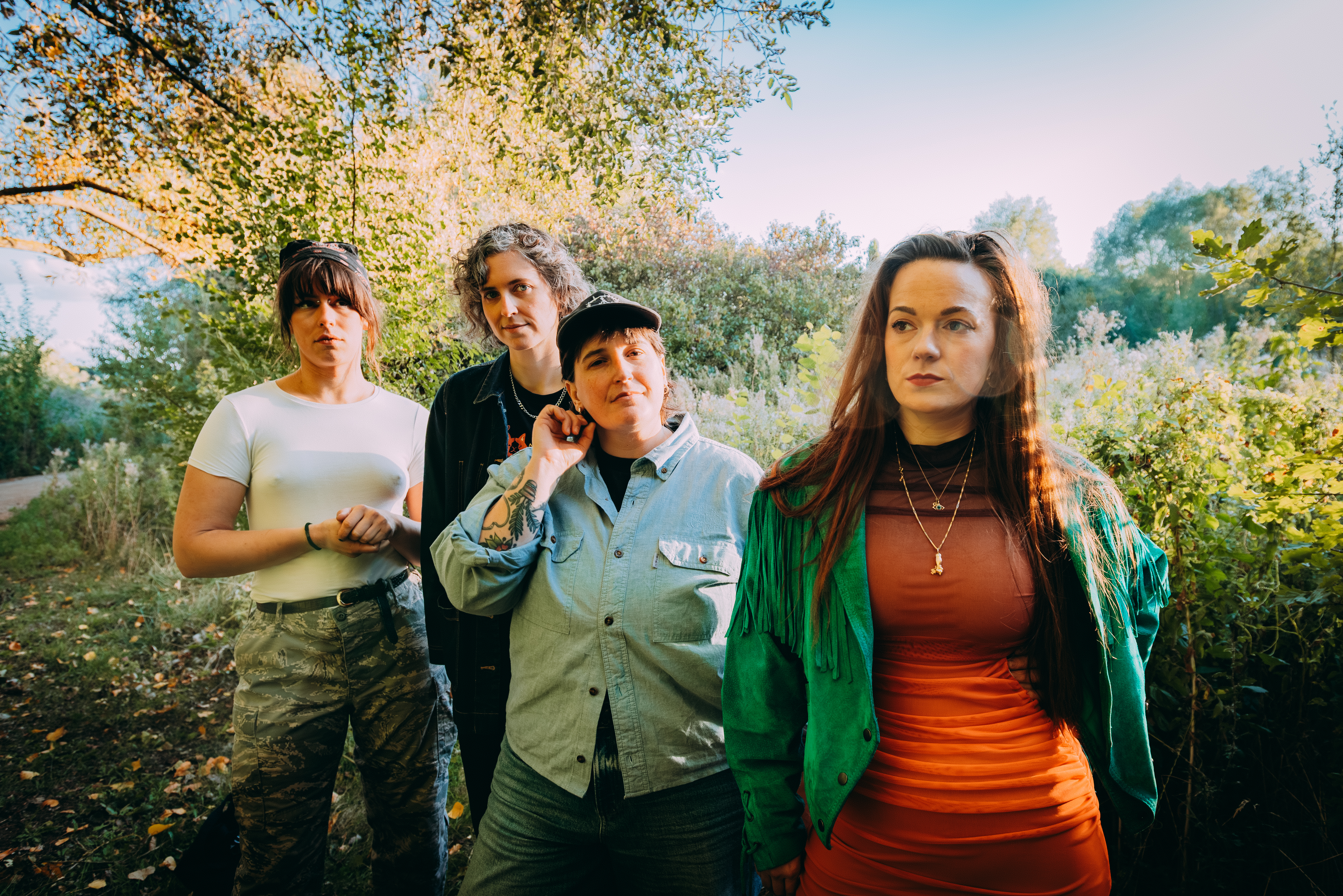 The four members of the band YAKKIE stood outside by a tree on a sunny day.